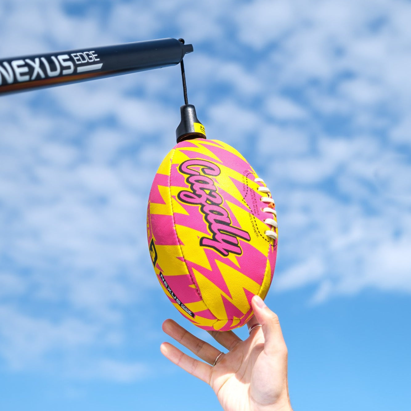 A person's hand attaches a Cazaly ball to the Nexus Edge ready for practising AFL skills
