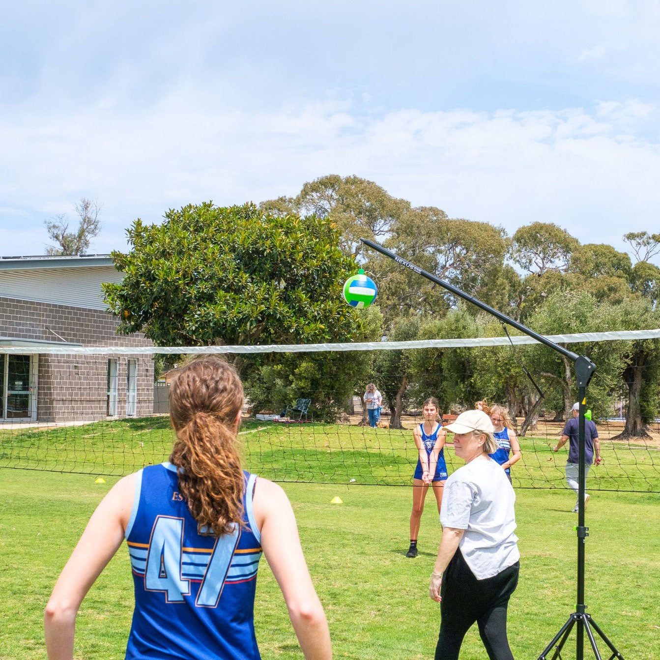 People practise volleyball skills on a grass oval using the Nexus Edge